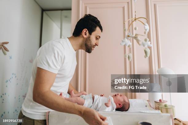 padre cambiando el pañal de su hija recién nacida en casa - man wearing diaper fotografías e imágenes de stock
