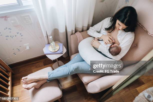 madre che allatta al seno la sua figlia appena nata a casa - allattamento foto e immagini stock