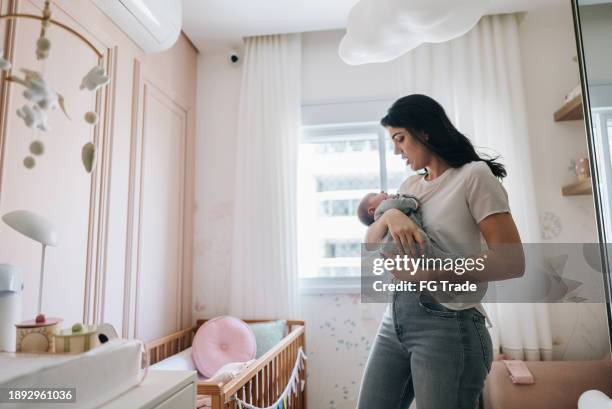 mother holding her newborn daughter at bedroom - lullaby stock pictures, royalty-free photos & images