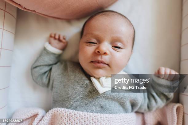 newborn baby girl lying down in her crib at bedroom - babymeisjes stockfoto's en -beelden