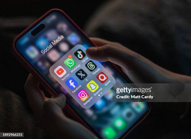 Year-old boy looks at an iPhone screen showing various social media apps including TikTok, Facebook and X, on December 19, 2023 in Bath, England. The...