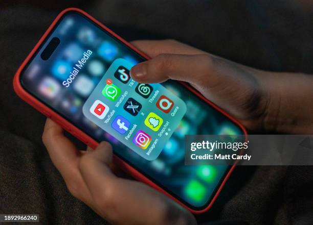 Year-old boy looks at an iPhone screen showing various social media apps including TikTok, Facebook and X, on December 19, 2023 in Bath, England. The...