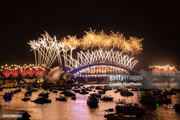 Fireworks are lighting up the sky over the Sydney Harbour Bridge and the Sydney Opera House during New Year's Eve celebrations in Sydney, Australia,...