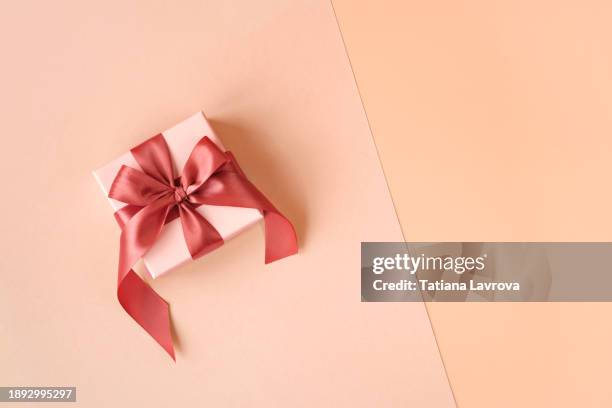 gift box with satin ribbon on festive paper background with copy space. valentines day, international women day, mothers day concept. demonstrating trendy color 2024 peach fuzz - glitter fruit stock pictures, royalty-free photos & images