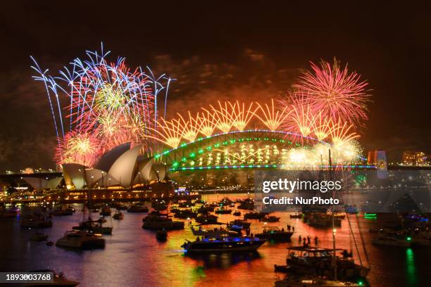 Fireworks are lighting up the sky over the Sydney Harbour Bridge and the Sydney Opera House during New Year's Eve celebrations in Sydney, Australia,...