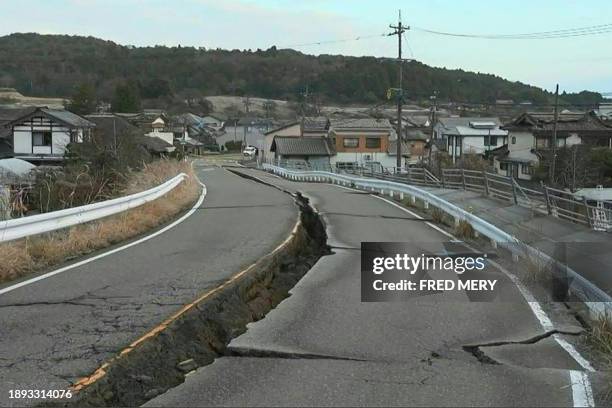This screen grab from AFPTV video footage taken on January 2, 2024 shows cracks in the road in the Japanese city of Nanao, Ishikawa prefecture after...