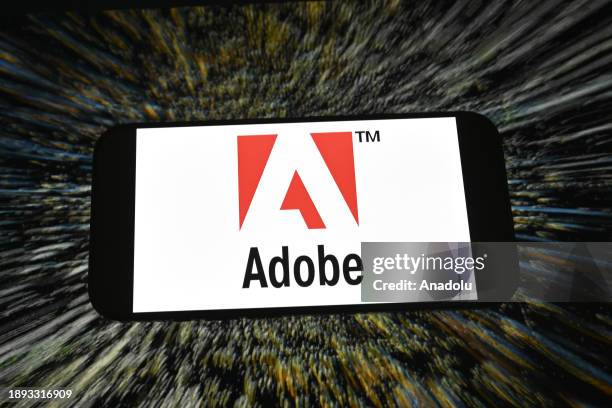 In this photo illustration logo of 'Adobe' app is displayed on a mobile screen in front of a computer screen in Ankara, Turkiye on December 28, 2023.