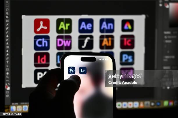 In this photo illustration logos of 'Adobe' apps are displayed on a mobile screen in front of a computer screen in Ankara, Turkiye on December 28,...