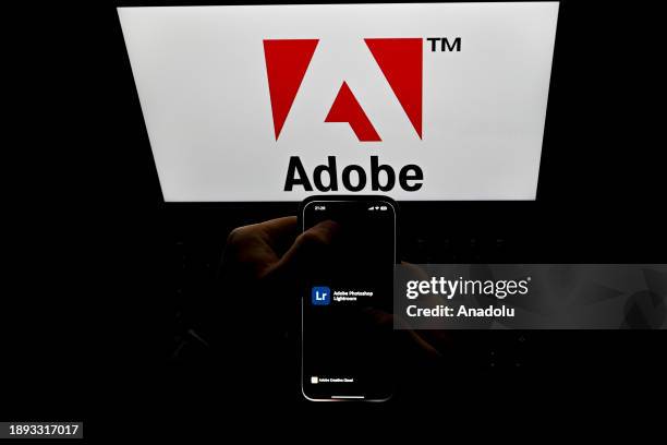 In this photo illustration logos of 'Adobe' apps are displayed on a mobile screen in front of logo of 'Adobe' on a computer screen in Ankara, Turkiye...