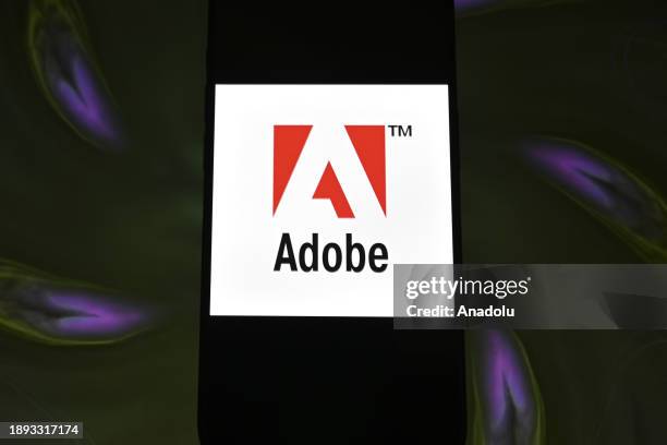 In this photo illustration logo of 'Adobe' app is displayed on a mobile screen in front of a computer screen in Ankara, Turkiye on December 28, 2023.