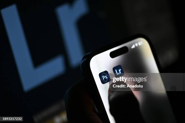 In this photo illustration logos of 'Adobe' apps are displayed on a mobile screen in front of a computer screen in Ankara, Turkiye on December 28,...