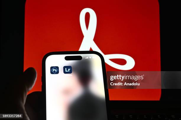 In this photo illustration logos of 'Adobe' apps are displayed on a mobile screen in front of logo of 'Adobe' on a computer screen in Ankara, Turkiye...