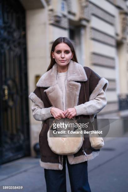Diane Batoukina wears blue flared wide-leg jeans by Massimo Dutti, a sleeveless / pagoda sleeved aviator brown jacket with sheep wool inner lining...