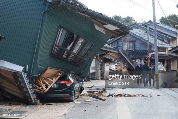 People walk past a badly damaged house in the city of Nanao, Ishikawa Prefecture, on January 2 a day after a major 7.5 magnitude earthquake struck...