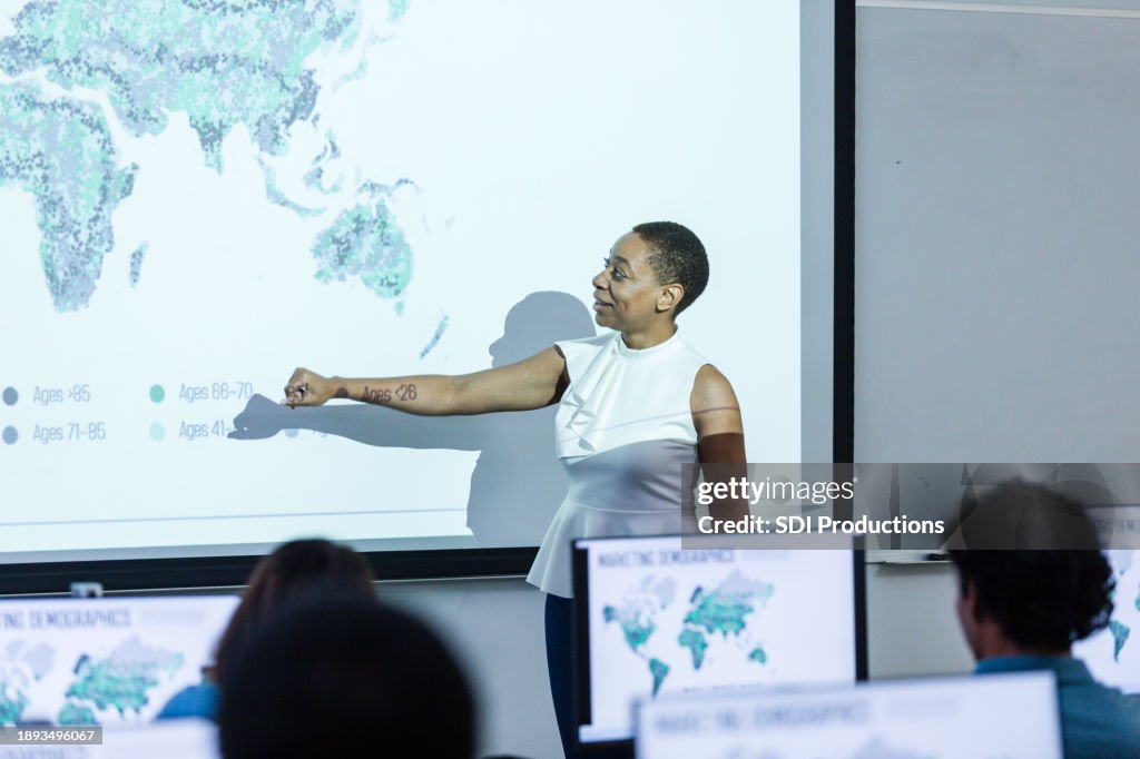 Unrecognizable businesspeople attend lecture by businesswoman on global marketing