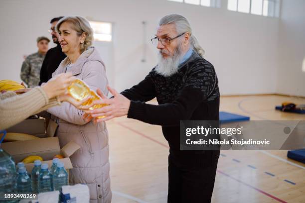 refugees at a help center - man holding donation box stock pictures, royalty-free photos & images