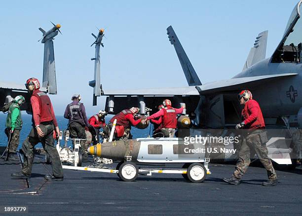 Aviation Ordnancemen move ordnance to nearby aircraft as another crew of Aviation Ordnancemen load ordnance onto an F/A-18E Super Hornet April 2,...