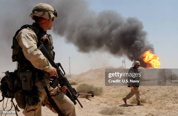 Army Sgt. Mark Phiffer stands guard duty April 2, 2003 near a burning oil well in the Rumaylah Oil Fields in Southern Iraq. Coalition forces have...