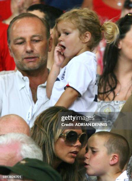 Wife of English midfielder David Beckham, Victoria , speaks to their son Brooklyn as their son Romeo looks on with an unidentified man following the...