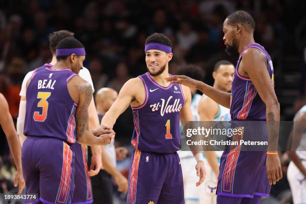 Devin Booker of the Phoenix Suns celebrates with Bradley Beal and Kevin Durant after scoring against the Charlotte Hornetsduring the second half of...