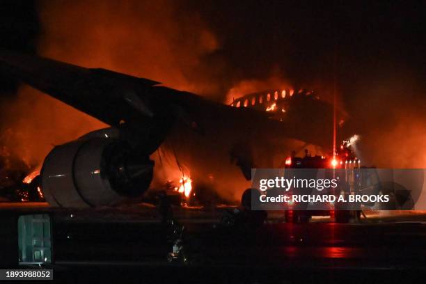 Fire engine is seen beside a Japan Airlines passenger plane on the tarmac at Tokyo International Airport at Haneda on January 2, 2024. A Japan...