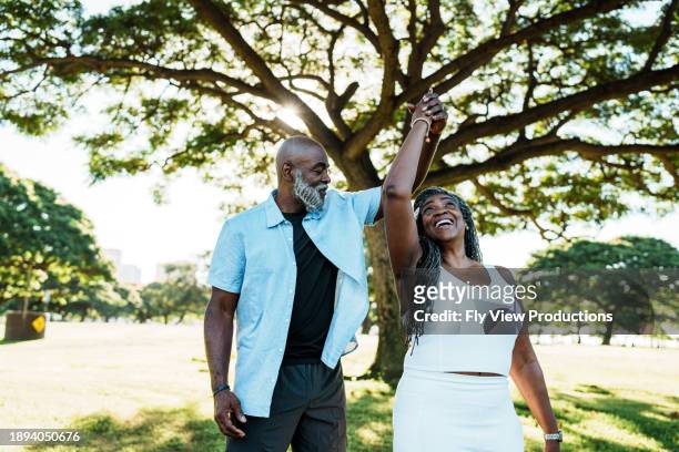 playful and loving senior couple dancing at the park - dancing couple stock pictures, royalty-free photos & images
