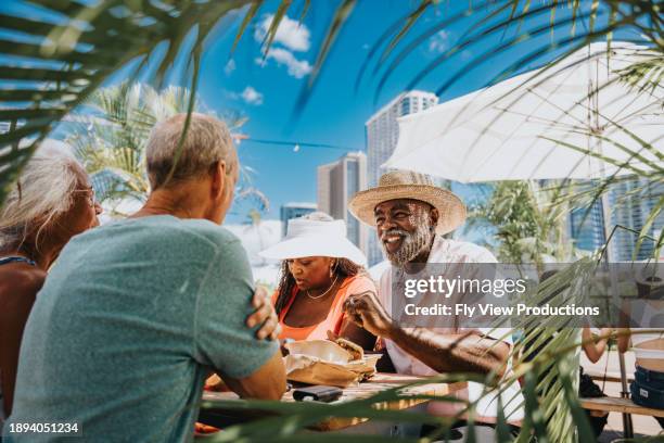 African American senior couple eating street food with friends in Hawaii