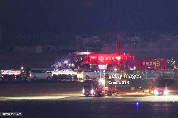 This photo provided by Jiji Press shows firefighters working at the scene of an accident between a Japan Airlines plane and a coast guard aircraft on...