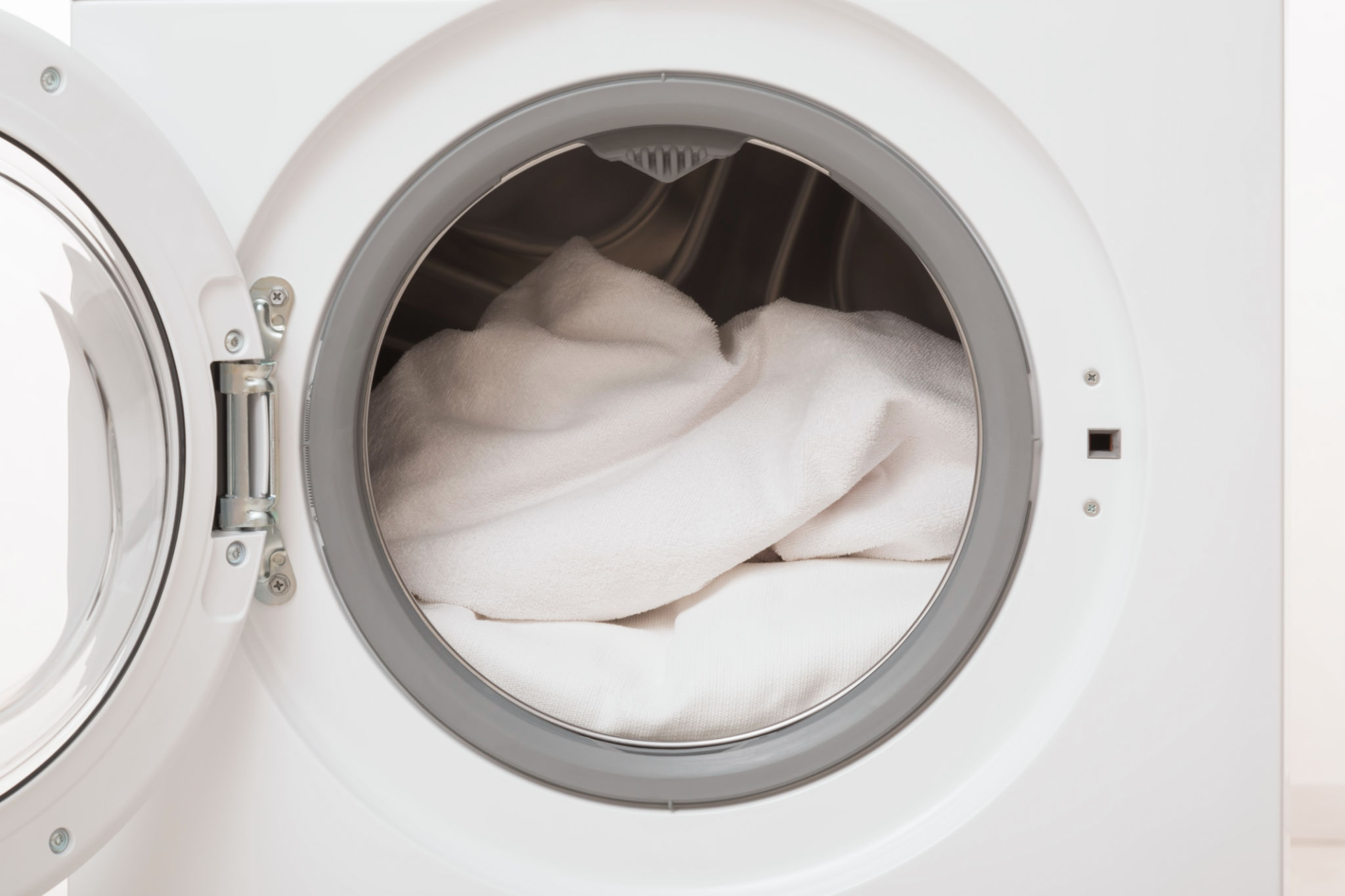 Opened washing machine full of white clothes. Closeup. Front view. Opened washing machine full of white clothes. Closeup. Front view.