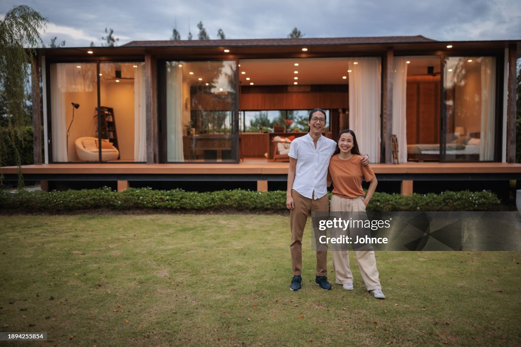 Smiling young couple in front of their home