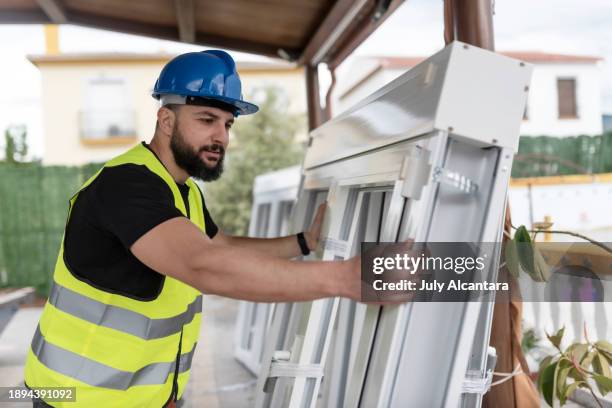 construction worker prepares the aluminum window frames to be placed on the construction site - timmerman stockfoto's en -beelden