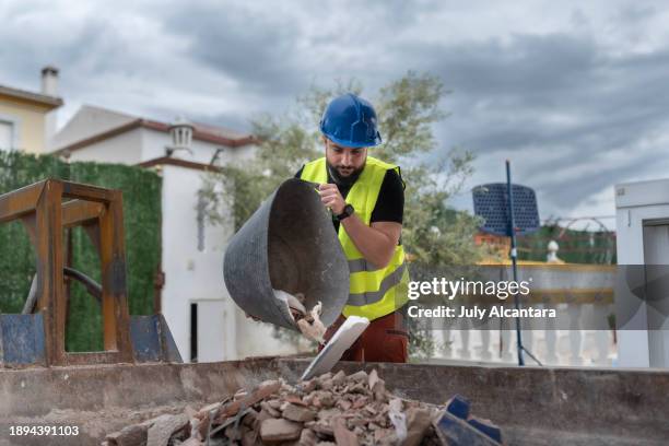 construction worker throws debris into a container outdoors when doing a renovation - skip bin stock pictures, royalty-free photos & images