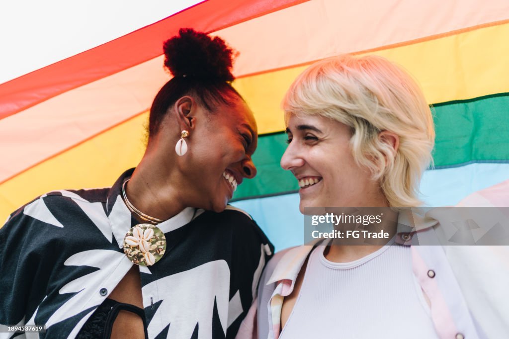 Lesbian couple face to face with rainbow flag on background