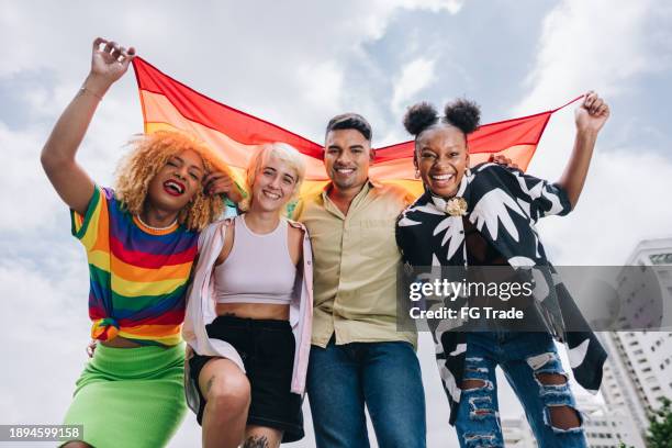 portrait d’un ami lgbtqia+ tenant un drapeau arc-en-ciel à l’extérieur - mois des fiertés lgbtqia photos et images de collection