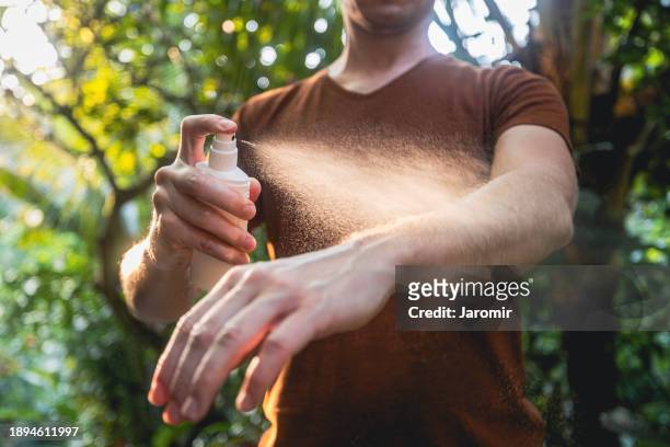 man while applying insect repellent - dengue fotografías e imágenes de stock