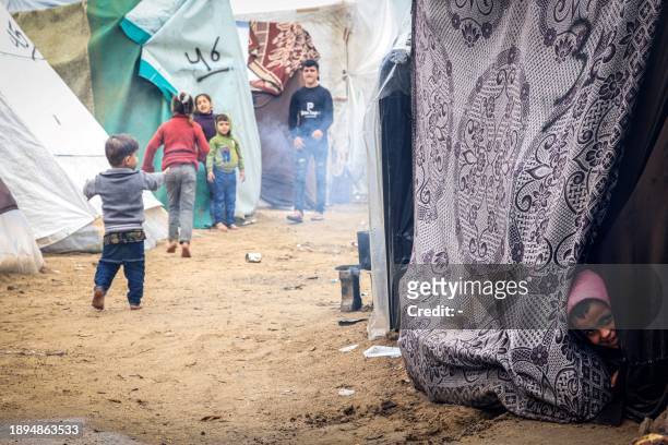 Palestinian child looks out of a tent at a makeshift camp housing displaced Palestinians, in Rafah in the southern Gaza Strip, amid the ongoing...