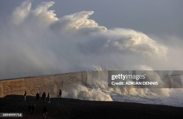 People watch as waves crash against the breakwater in Newhaven on January 2 as Storm Henk brought strong winds and heavy rain across much of southern...