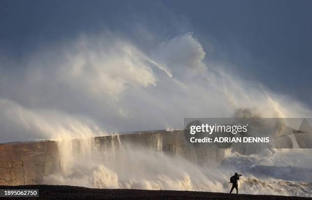 Person takes photographs of the sea as waves crash against the breakwater in Newhaven on January 2 as Storm Henk was set to bring strong winds and...