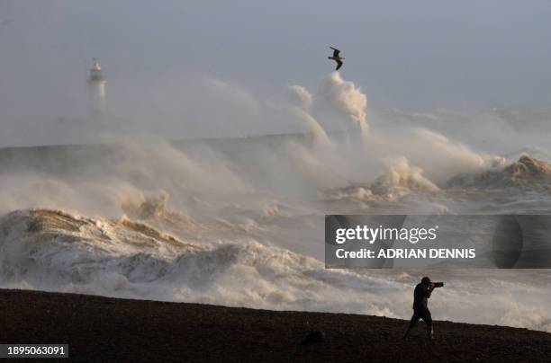 Person takes photographs of the sea as waves crash against the breakwater in Newhaven on January 2 as Storm Henk was set to bring strong winds and...