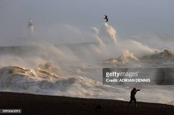 Person takes photographs of the sea as waves crash against the breakwater in Newhaven on January 2 as Storm Henk was set to bring strong winds and...