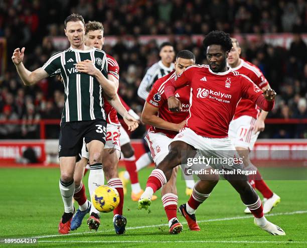 Jonny Evans of Manchester United is challenged by Ola Aina of Nottingham Forest during the Premier League match between Nottingham Forest and...