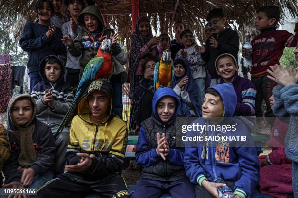 Displaced Palestinians pose for a picture with a parrot at the zoo in Rafah in the southern Gaza Strip, on January 2 where they sought refuge amid...