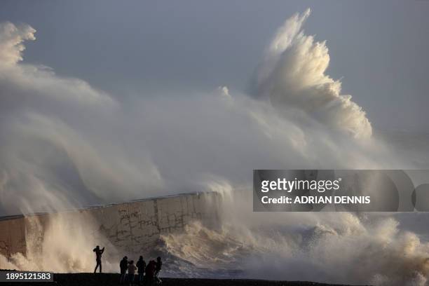 Person takes a photograph as waves break against the breakwater in Newhaven on January 2 as Storm Henk brought strong winds and heavy rain across...