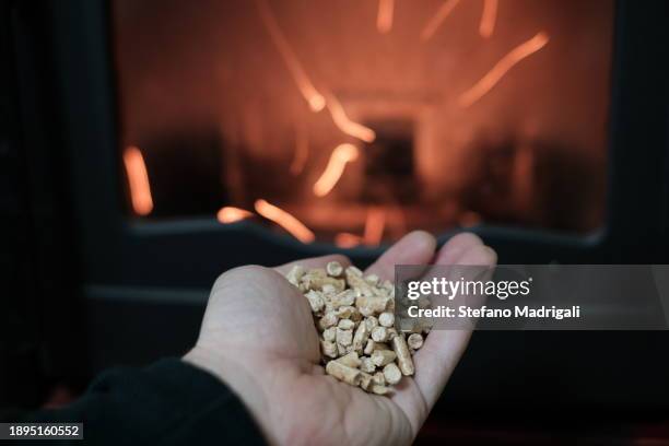 pellet in hand and stove on for heating - granule stockfoto's en -beelden