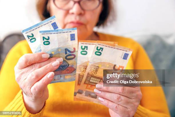 an elderly woman counting euro banknotes - euro stockfoto's en -beelden