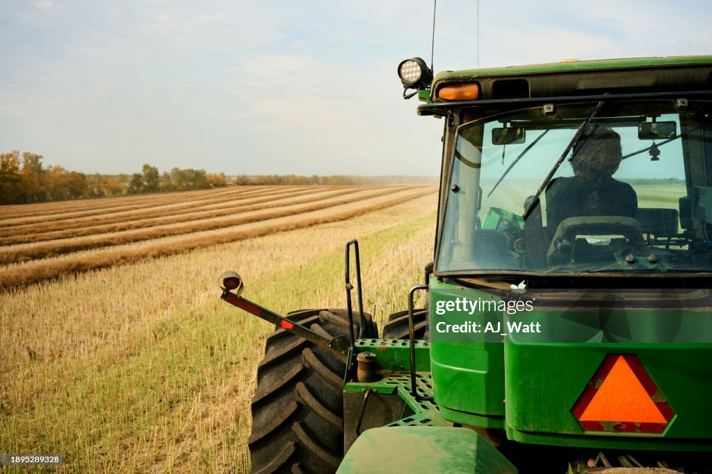Farmer driving tractor on agricultural farm field