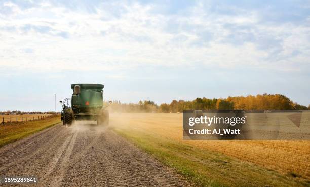 combine harvester driving along the dirt road on farm - track harvester stock pictures, royalty-free photos & images
