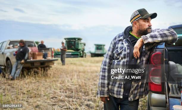 mid adult man standing outside by his pickup truck on farm field during break - agricultural equipment stock pictures, royalty-free photos & images