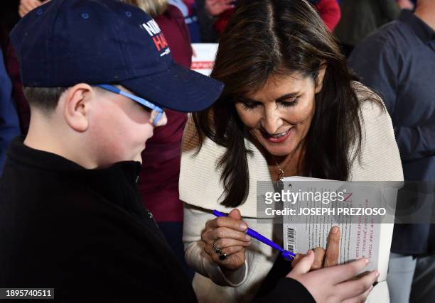 Former UN ambassador and 2024 Republican presidential hopeful Nikki Haley signs a book for young supporter Daniel Martin during a campaign town hall...