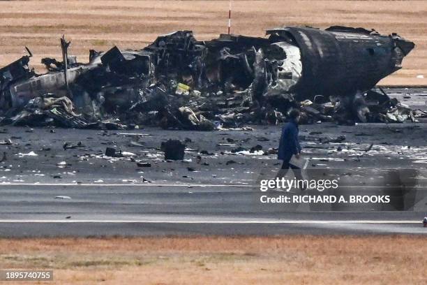 An official looks at the wreckage of a Japan coast guard plane on the tarmac at Tokyo International Airport at Haneda in Tokyo on January 3 the...